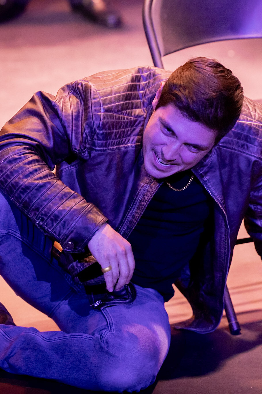 Man in leather jacket kneeling on stage